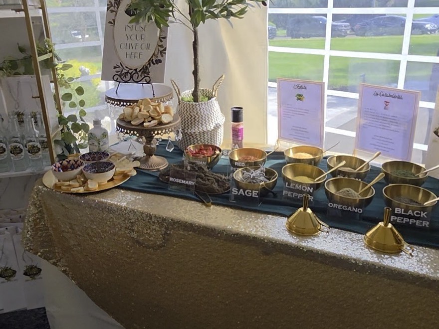 A grazing table under a marquee, dressed with a gold sequin linen and teal runner and laid with gold bowls of herbs and spices, breads and a tiered stand
