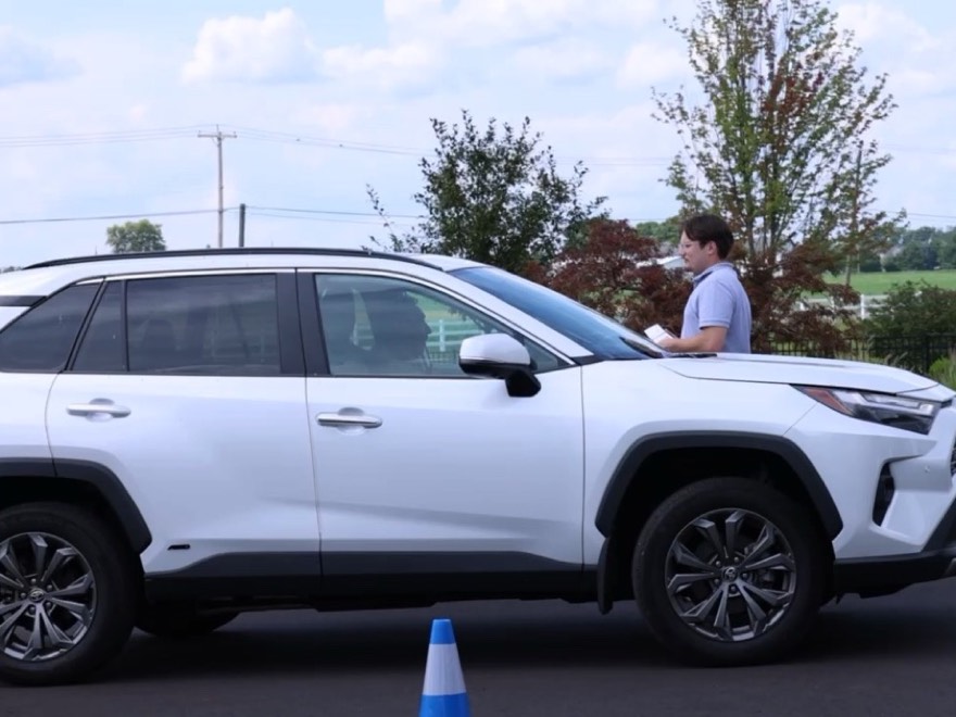 A guest car pulled up on the driveway at an at-home event, with an attendant and a cone marking the arrival lane
