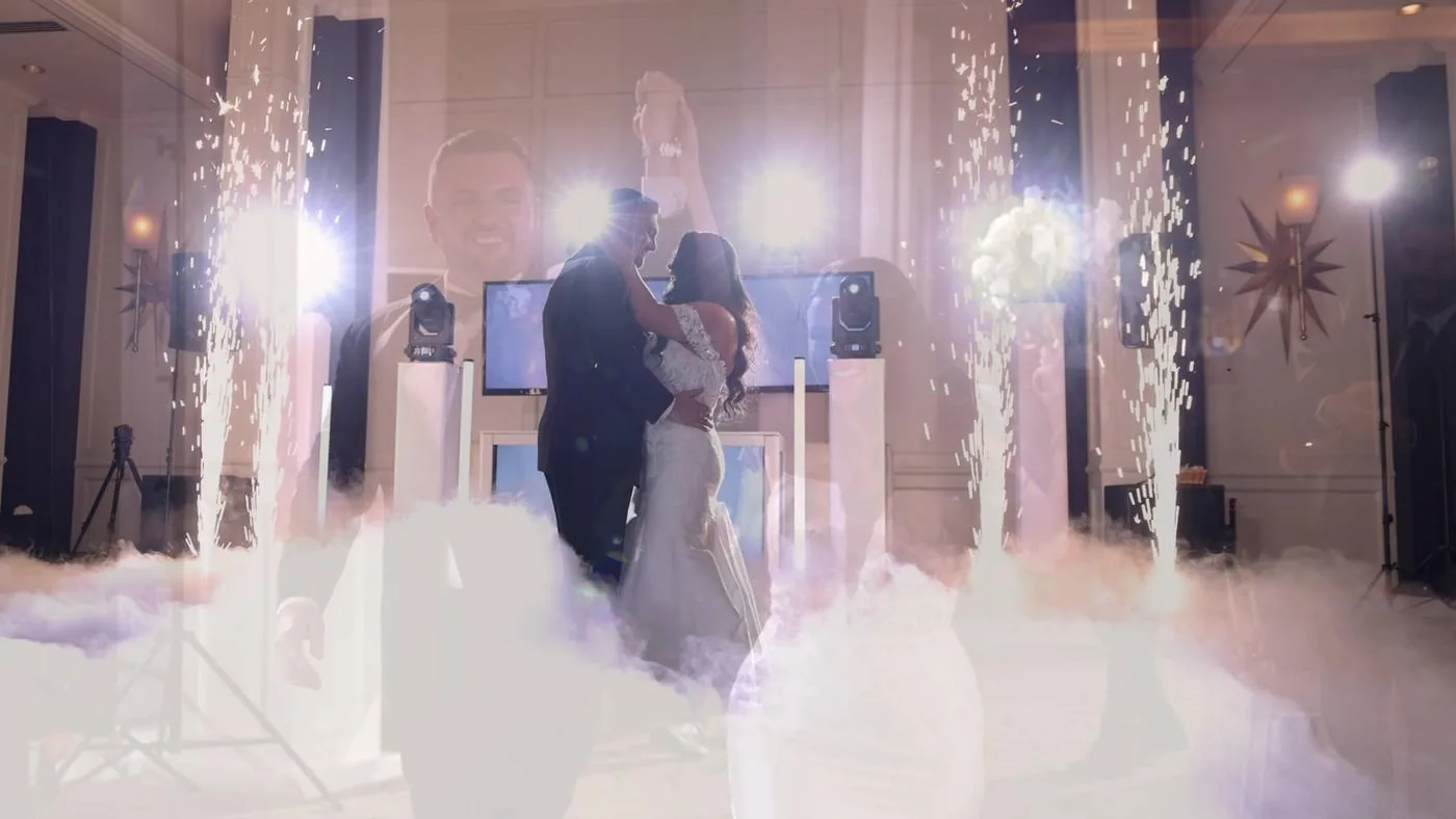 Couple's first dance surrounded by low dry-ice fog, with cold spark fountains firing on either side of them