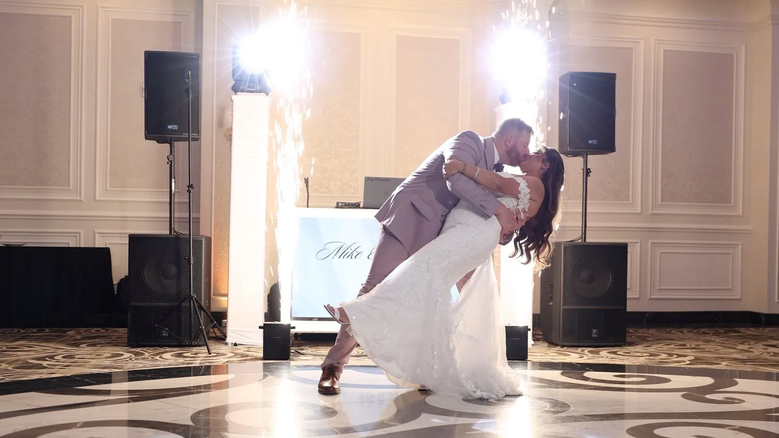 A first dance dip on the marble dance floor at The Meadow Wood, with cold spark fountains firing and the DJ booth and speakers behind