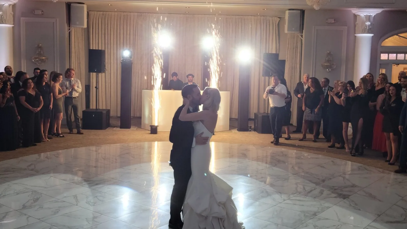 First dance at Valley Regency in Clifton NJ — cold spark fountains behind the couple on the white marble dance floor, under the ballroom chandeliers